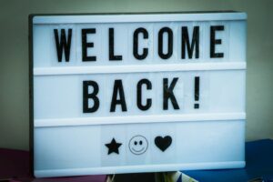 a welcome back sign with a smiley face